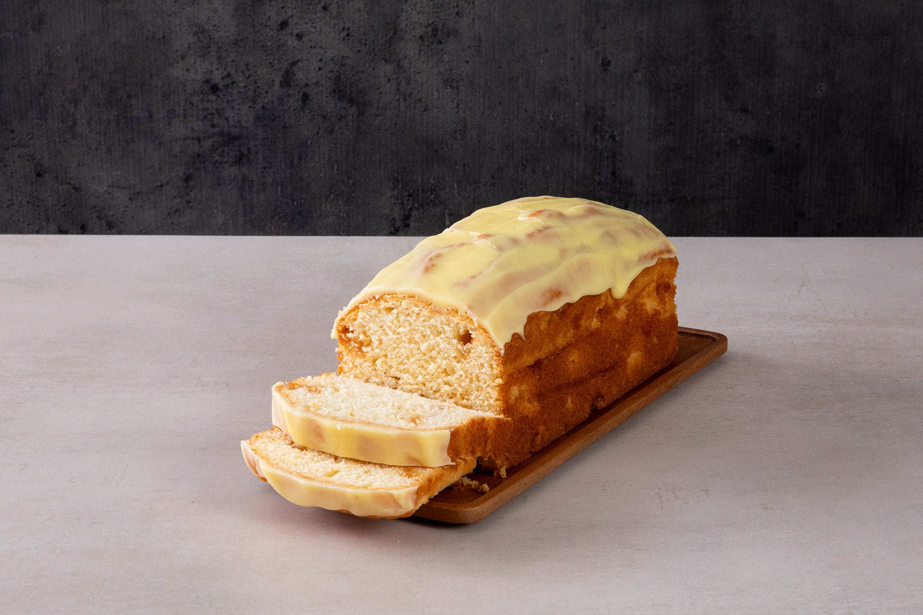 LHMC001-393.jpg Sliced lemon drizzle loaf cake with yellow icing glaze