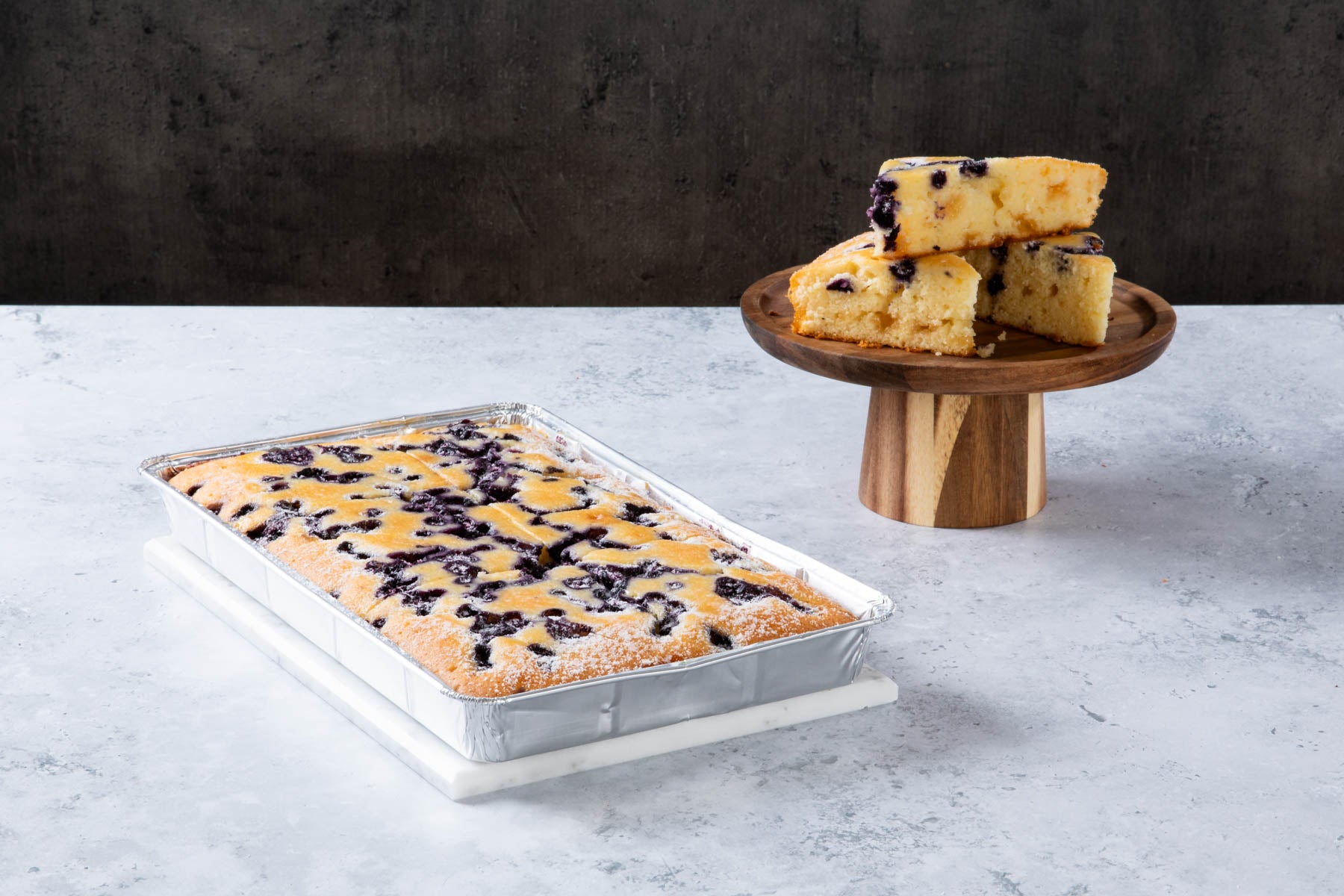 Blueberry crumble cake slices on a wooden cake stand and tray.