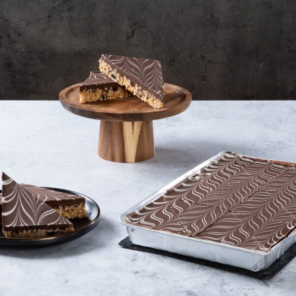 Chocolate crispy cake slices with marbled chocolate topping on a wooden stand.