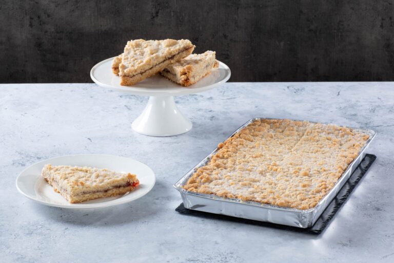 Chocolate cake with creamy frosting and chocolate topping on a wooden board.