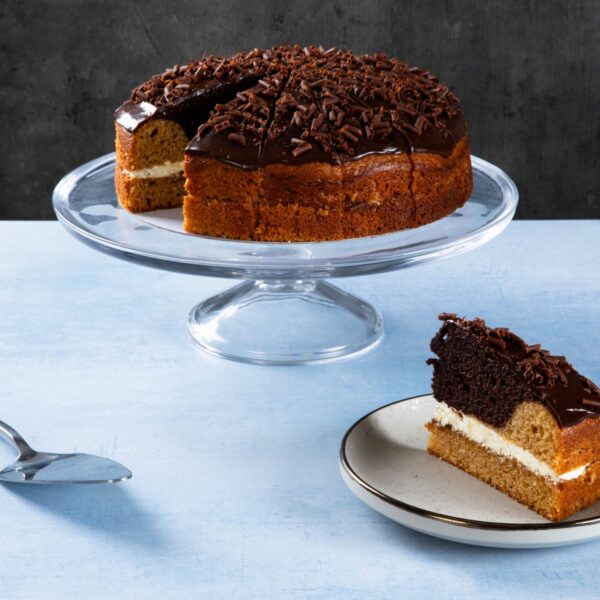 Lemon drizzle cake with lemon icing on a wooden board.