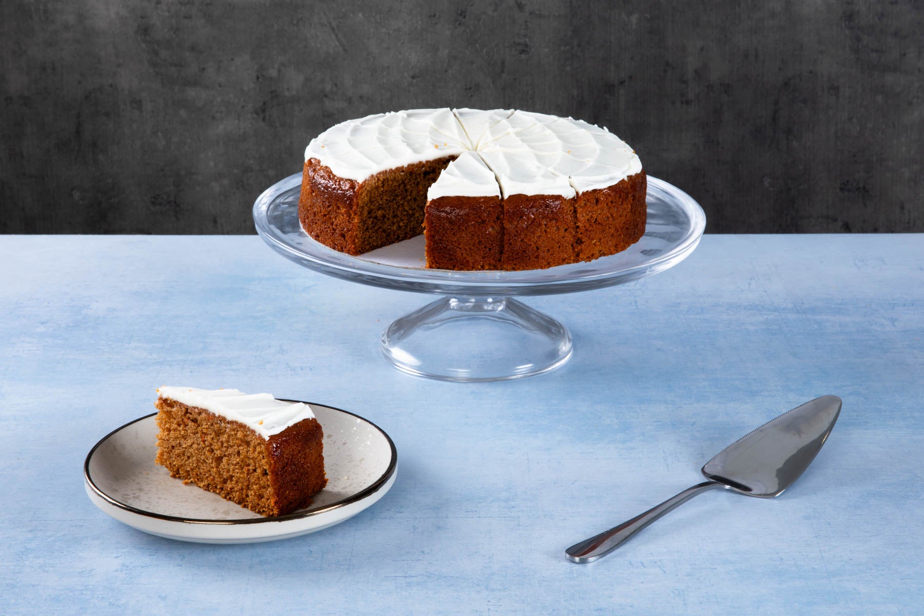 Chocolate cake with creamy frosting and chocolate topping on a wooden board.