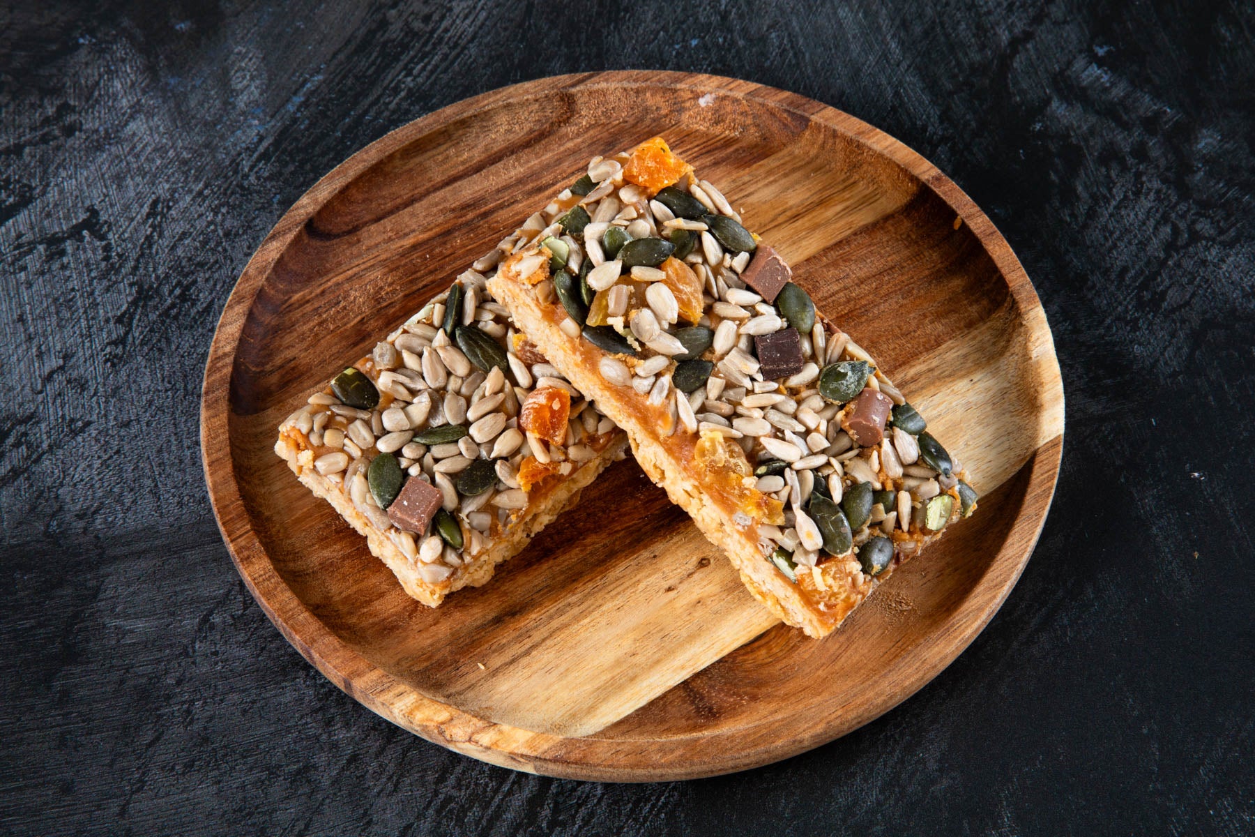 LHMC008-573.jpg Apricot and seed flapjack slices on a wooden plate.