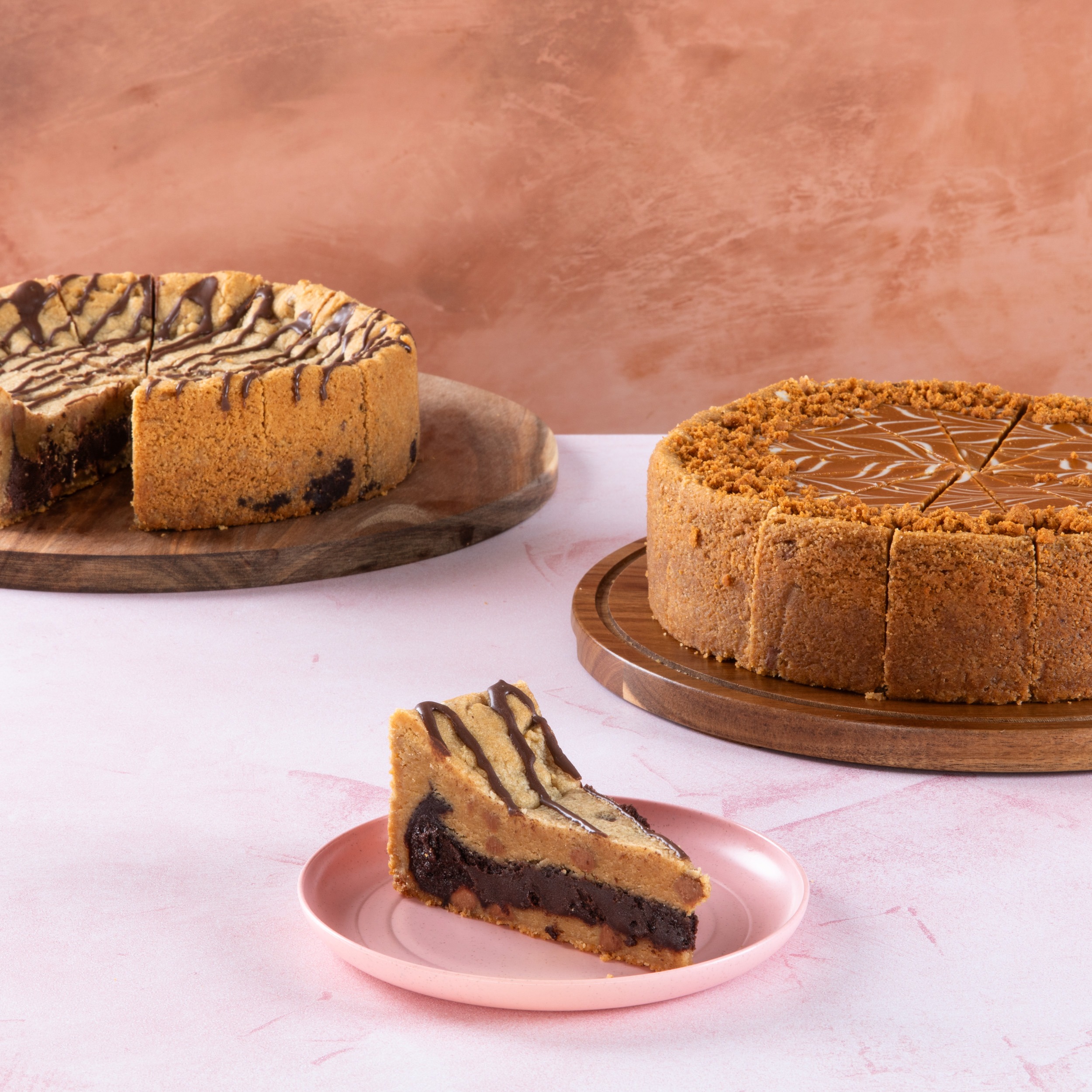 Chocolate brownie and caramel cakes with sliced pieces on wooden boards.